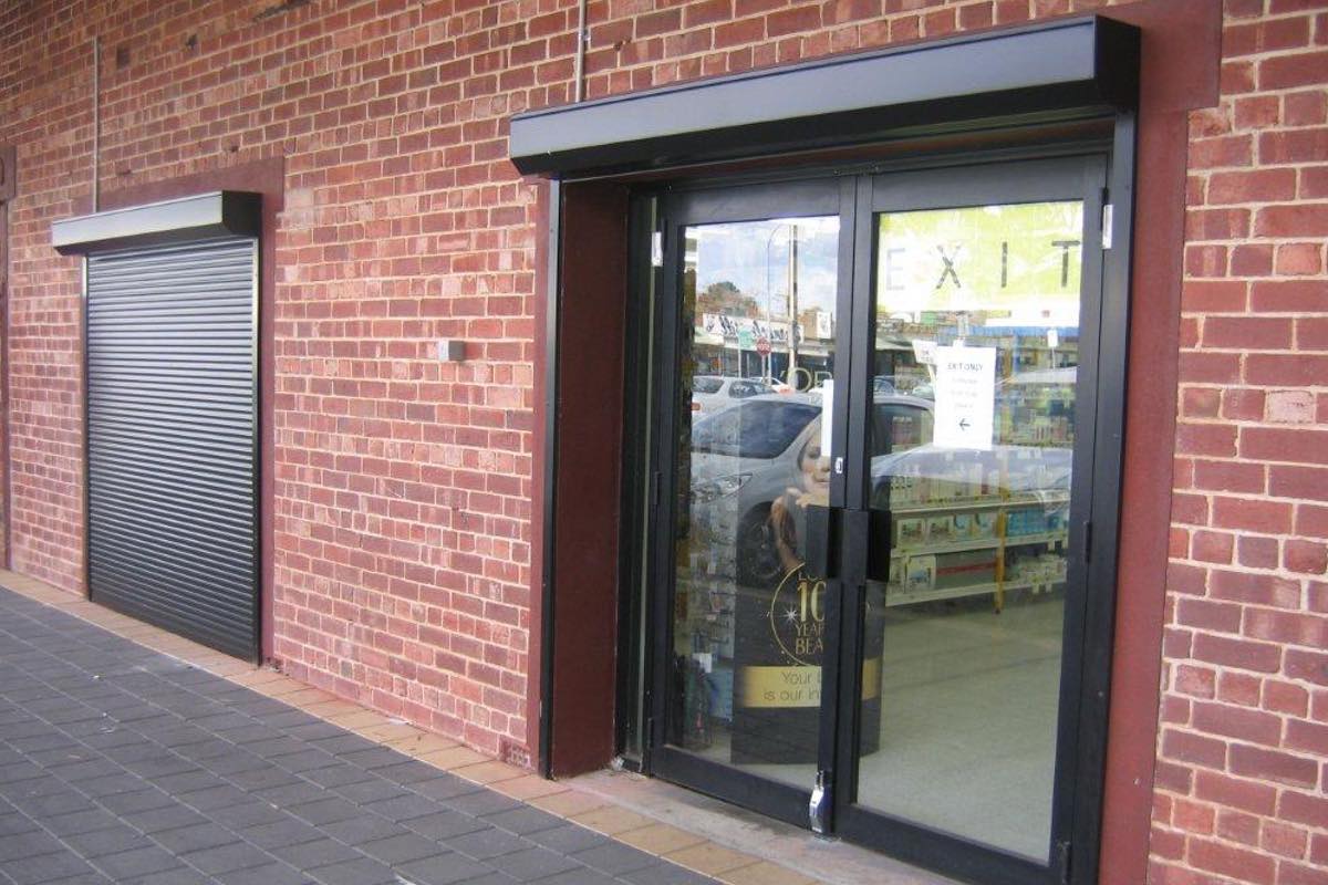 Black commercial roller shutters on chemist store